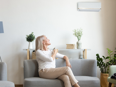 Lady sitting on couch turning air con on with remote